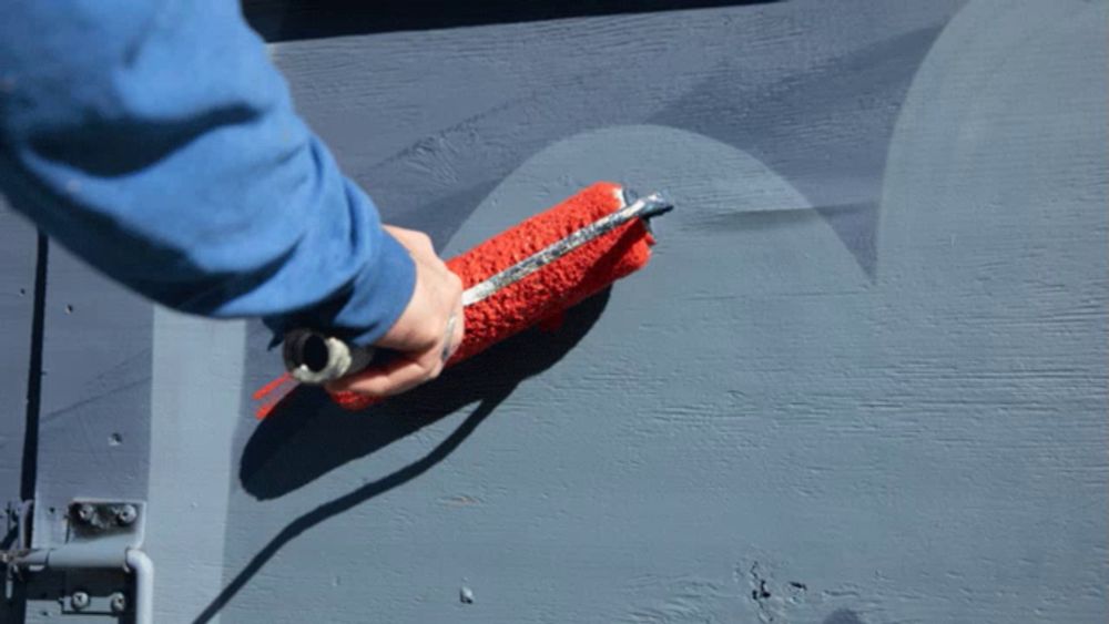 a person paints a wall with red paint