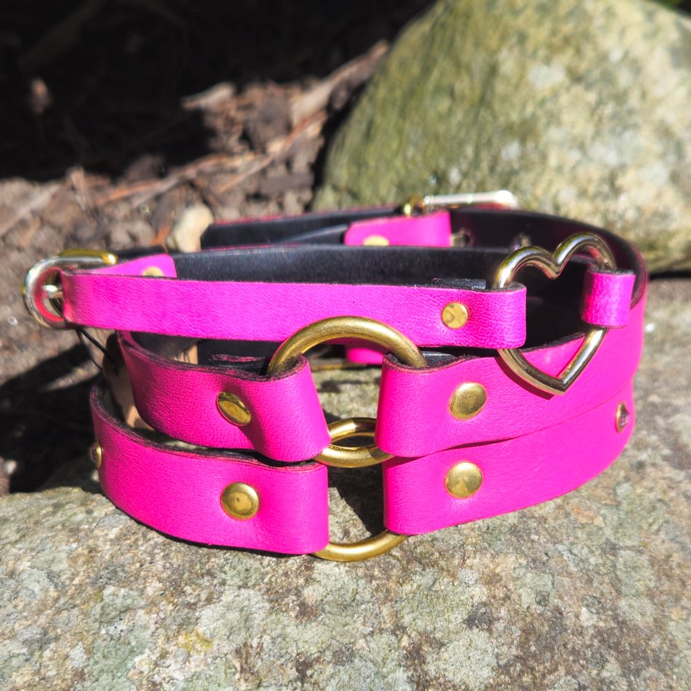 A stack of pink collars: two O-ring and one heart-ring-collar on top of a rock