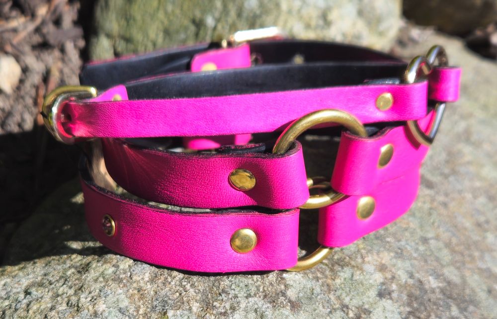 A stack of pink collars: two O-ring and one heart-ring-collar on top of a rock