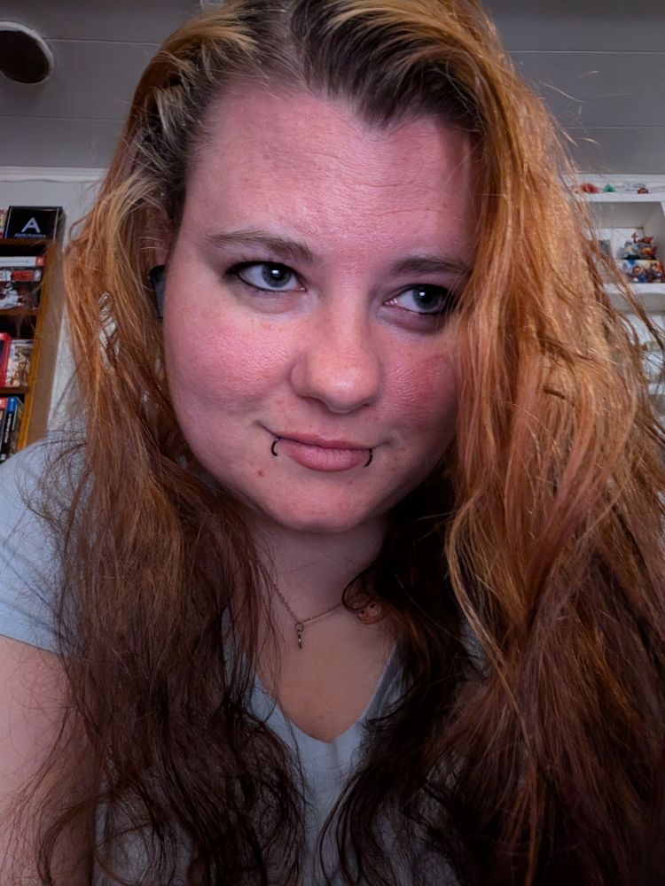 cassiterite! her blond-and-red hair cascades around her face, which is smiling. she is looking off camera.