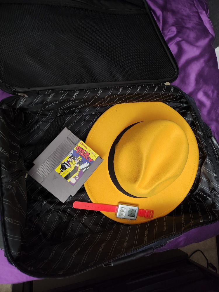 And open luggage case shows a yellow fedora, a two-way radio wristwatch, and a copy of Dick Tracy for NES.