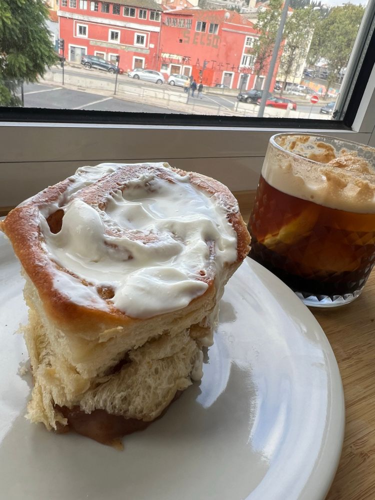 Cinnamon roll imenso do lado de copo com espresso tônica que fiz em casa