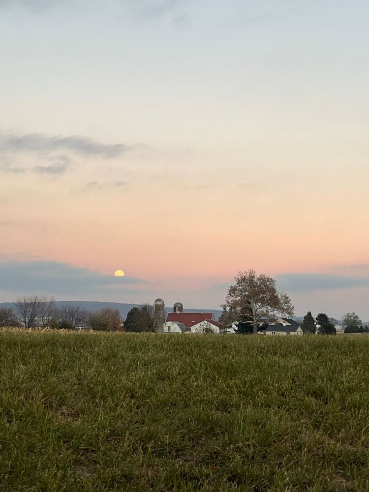 Full moon rising above farm