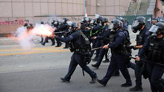 Riot cops in LA with batons out; helmets on, shooting munitions at protesters.