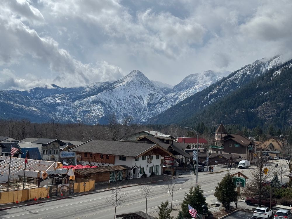 Mountains with snow and hills with evergreen trees and snow behind a Bavarian village