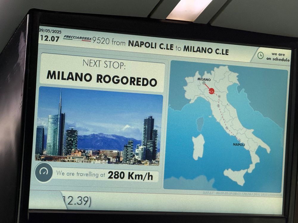 Overhead screen in Italian train, showing 280 Kilometers/hour speed and approaching Milano Rogoredo station