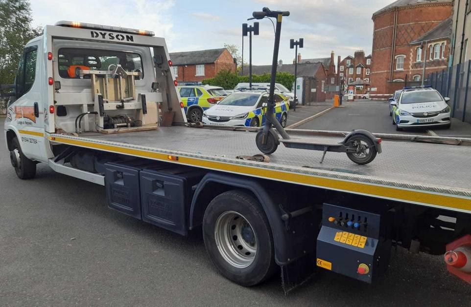 A single e-scooter sitting (securely) on a very long low-loader. 