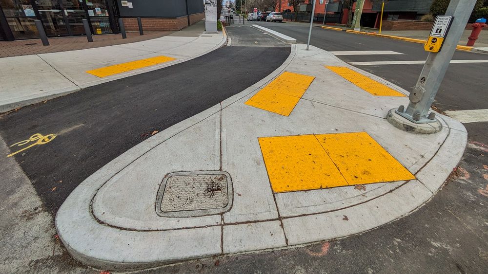 A view of the bicycle connection (with bike racks) and pedestrian island at the North side of the intersection of Hillside Avenue and Nanaimo Street.
