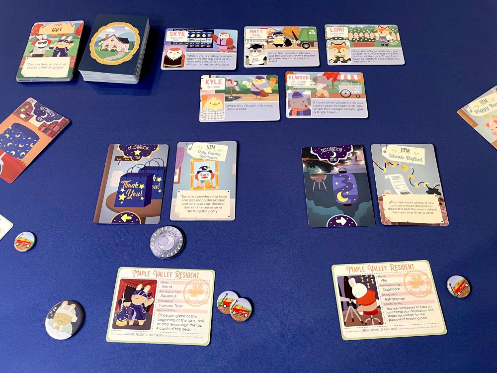 cards and tokens from the game "Bunny Party at Maple Valley" spread out on the table. The cards feature illustrations of cute animals and decorations for a party. 