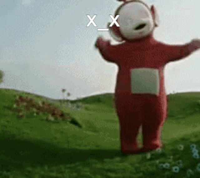 a red teletubbies character is standing in a grassy field