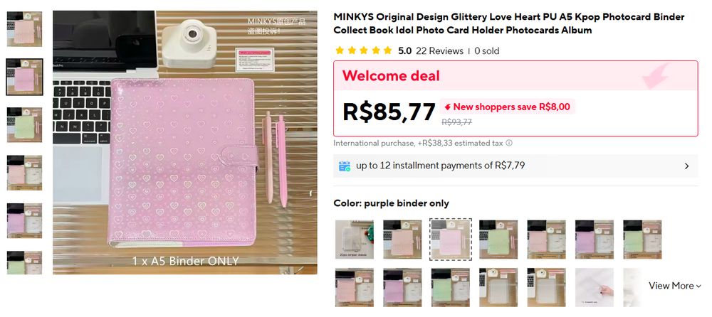 Print de anúncio do Aliexpress com foto de um fichário A5 lilás com corações holográficos. O preço com promoção de primeira compra é de R$85,77, e a taxa estimada é de R$38,33. 