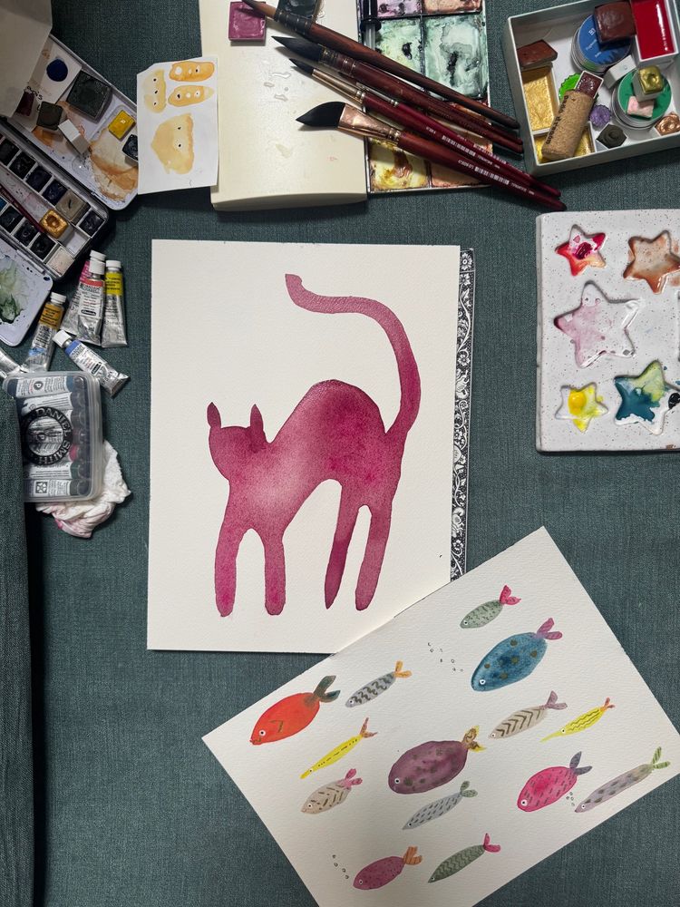 Paint supplies- palettes, brushes, tubes- and in progress cat with a sea of colorful fish below 