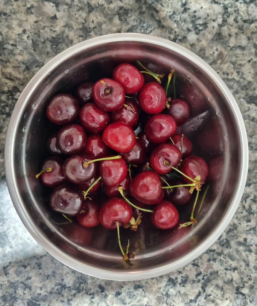 Cerejas frescas numa tigela de inox.