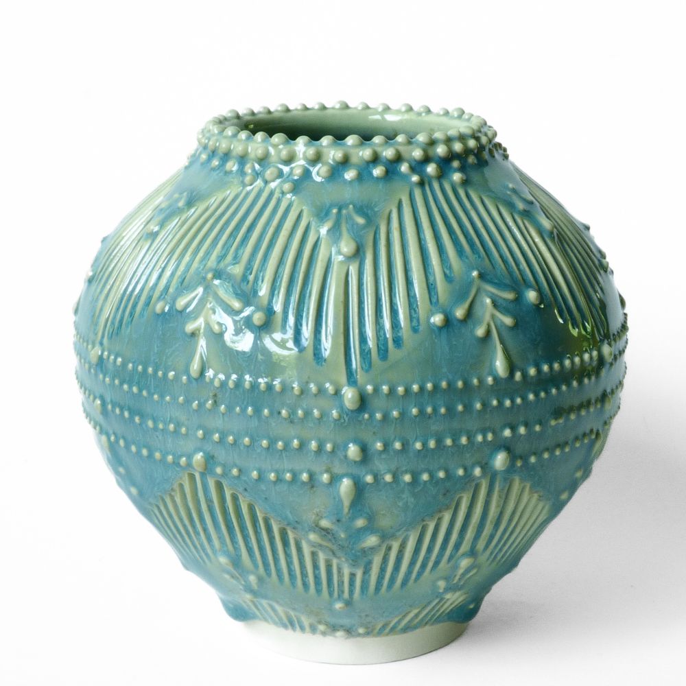 A round vase with geometric pattern created by carved lines and slip dots 