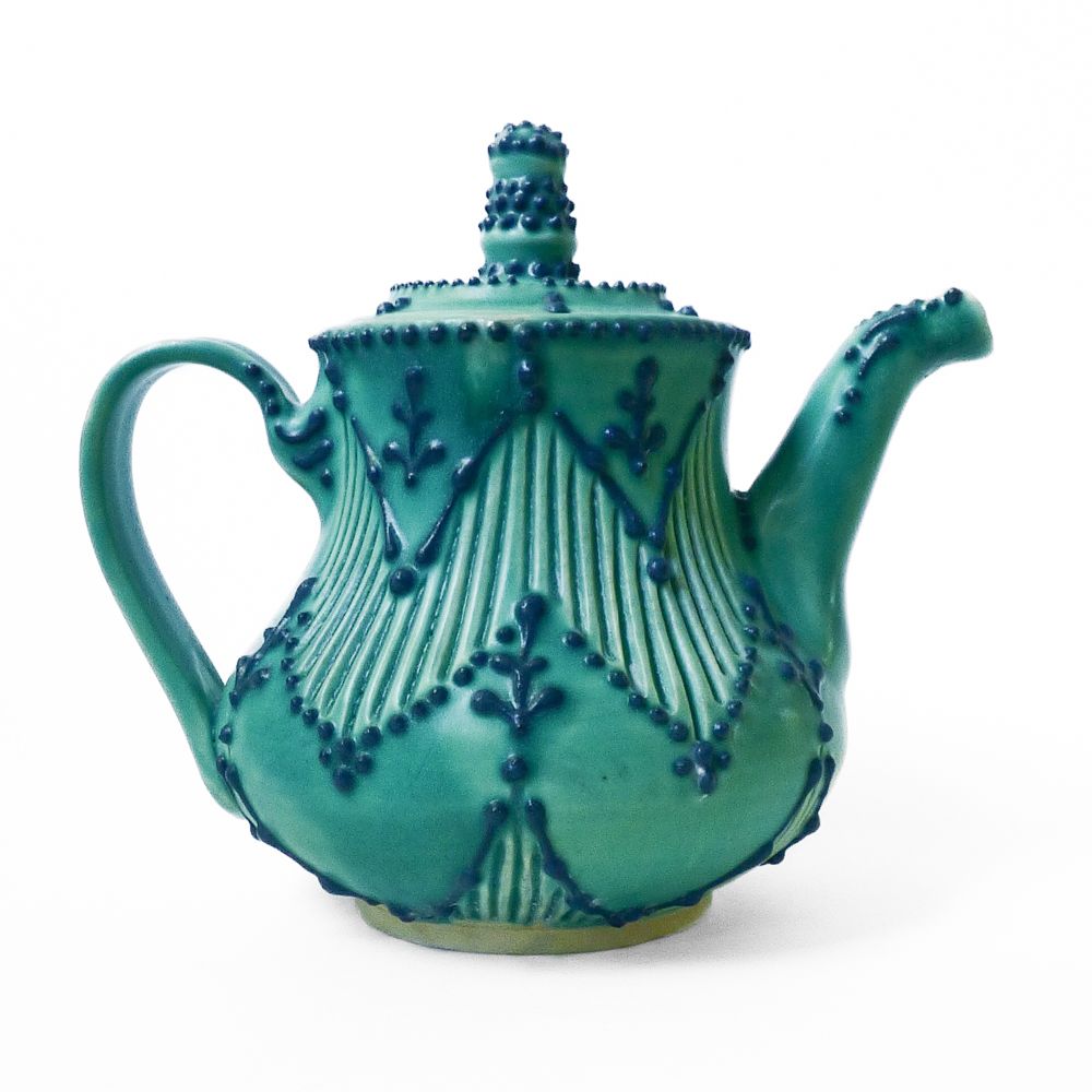 A small teacup in turquoise glaze with a blue slip trailed zig zag design 