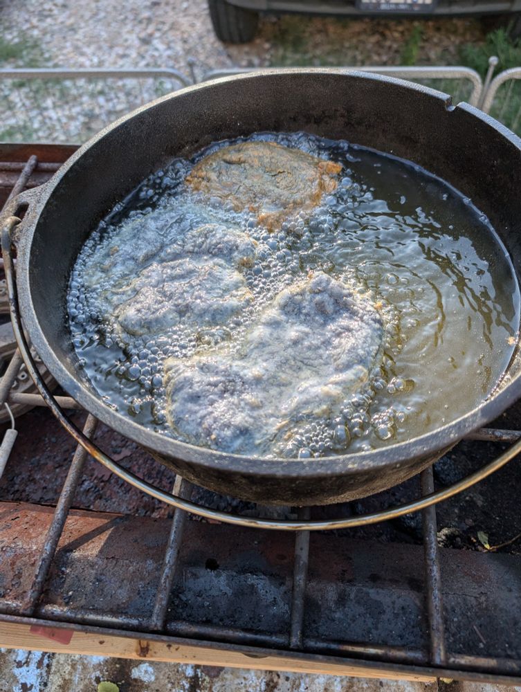 A Dutch oven with oil and pork fat frying up blue cornmeal and flour Navajo fry bread. 
