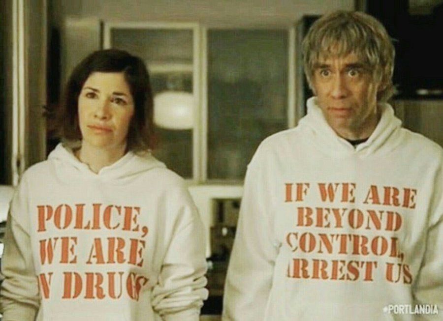 Two people wearing funny sweatshirts that read "Police, we are on drugs" from the episode "late in life drug use" from the show "Portlandia"