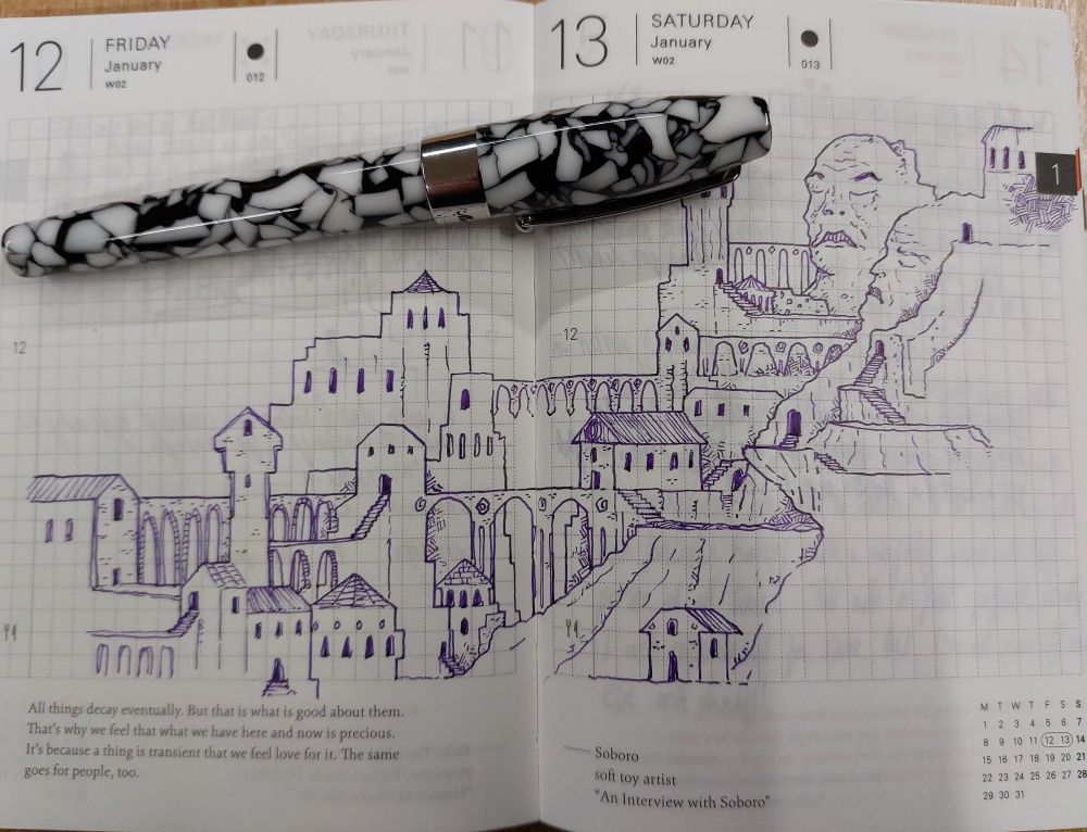 A black and white fountain pen sits on top of an open hobonichi journal, with a drawing of a city done in purple ink over both pages