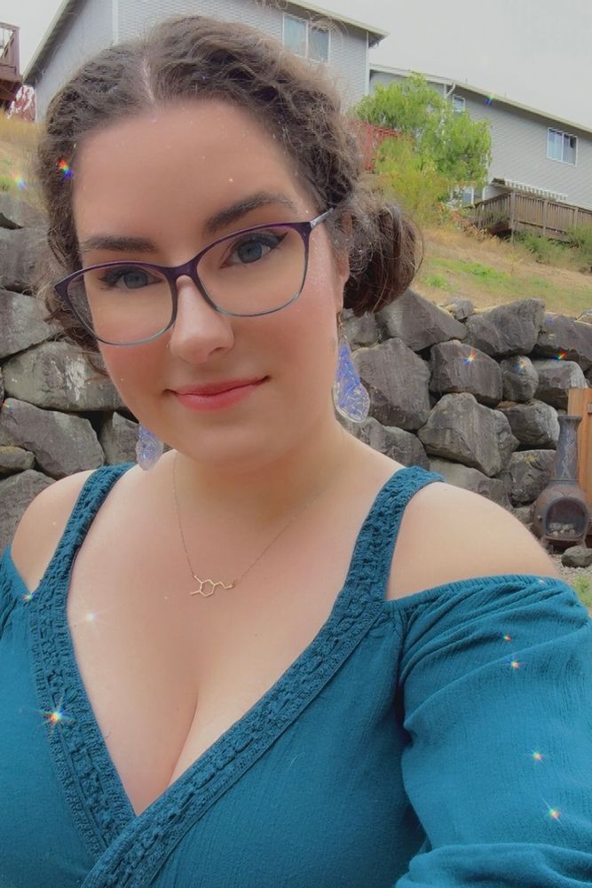 Selfie of Ghost in a sparkly filter wearing a blue off the shoulder top with her hair in low space buns 