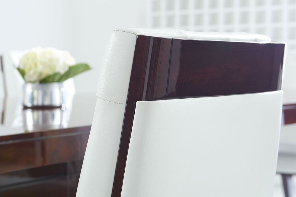 Close-up of a Decca dining chair showing glossy dark wood paired with smooth white upholstery, highlighting the brand’s craftsmanship, luxury furniture design, and modern elegance.