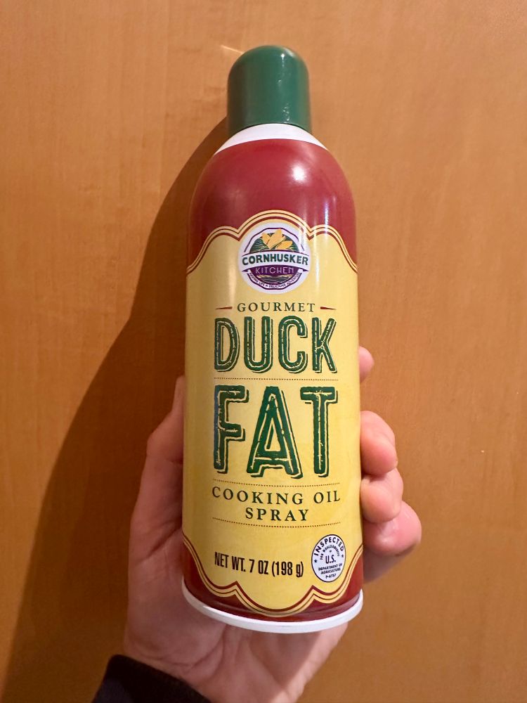 The author is holding a can of “Gourmet Duck Fat Cooking Oil Spray”. 