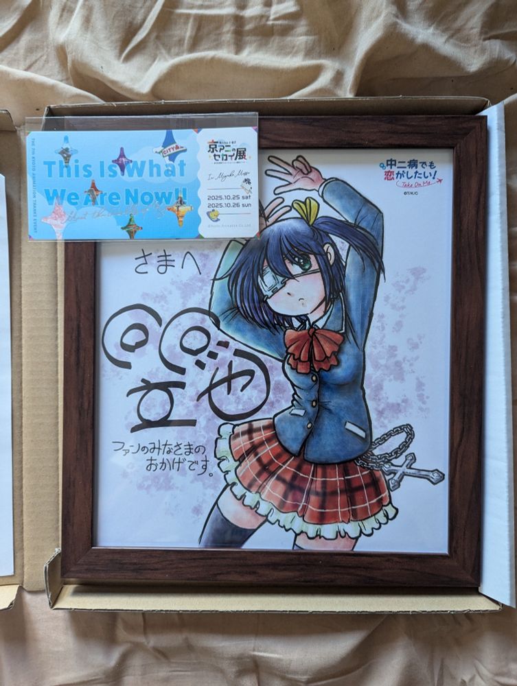 a framed drawing of takanashi rikka from chuunibyou demo koi ga shitai signed by the artist. on top is a ticket to the Kyoani no Sekai event