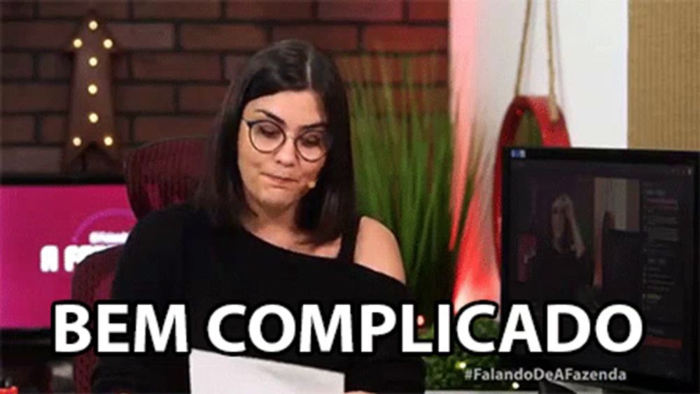 a woman wearing glasses is sitting at a desk in front of a computer and a microphone .