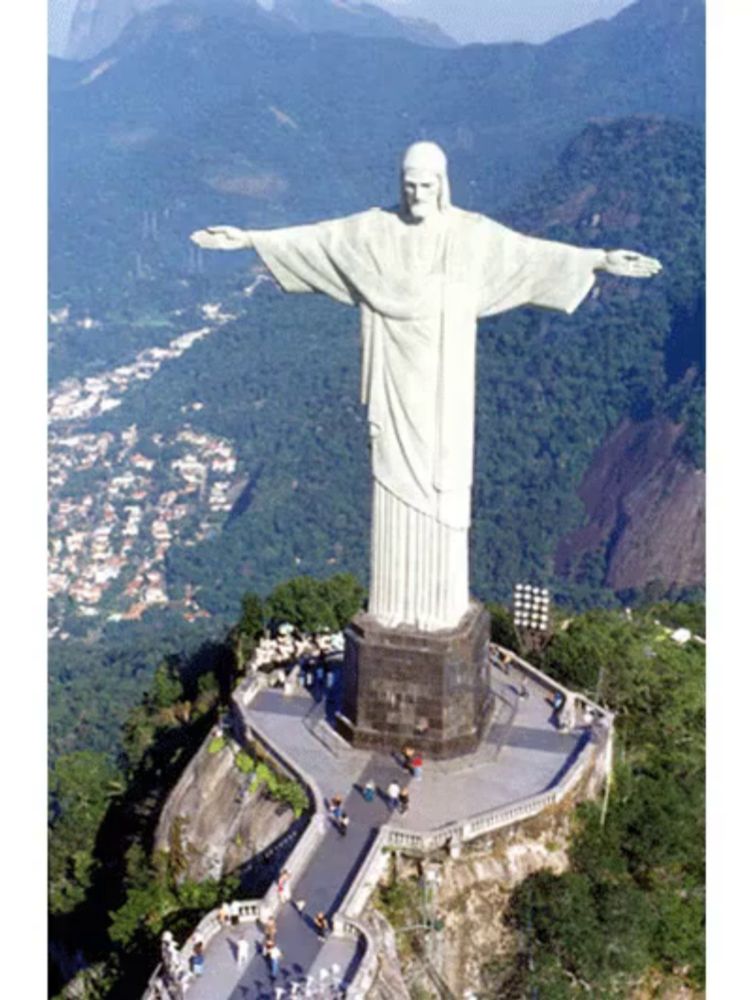 a large white statue of jesus stands on top of a hill