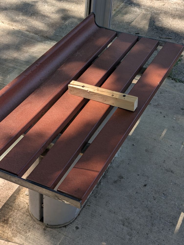 A single, unpainted piece of wood maybe a foot and a half long screwed into a brown plastic bench. The screws have split the wood in half, though it's still holding together. They didn't even try.