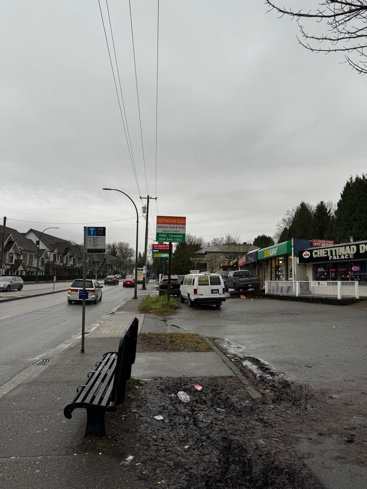 Canada way a four lane stroad with car oriented retail and some recently built townhouses that front onto the busy street. A sad muddy bus stop is in the front 