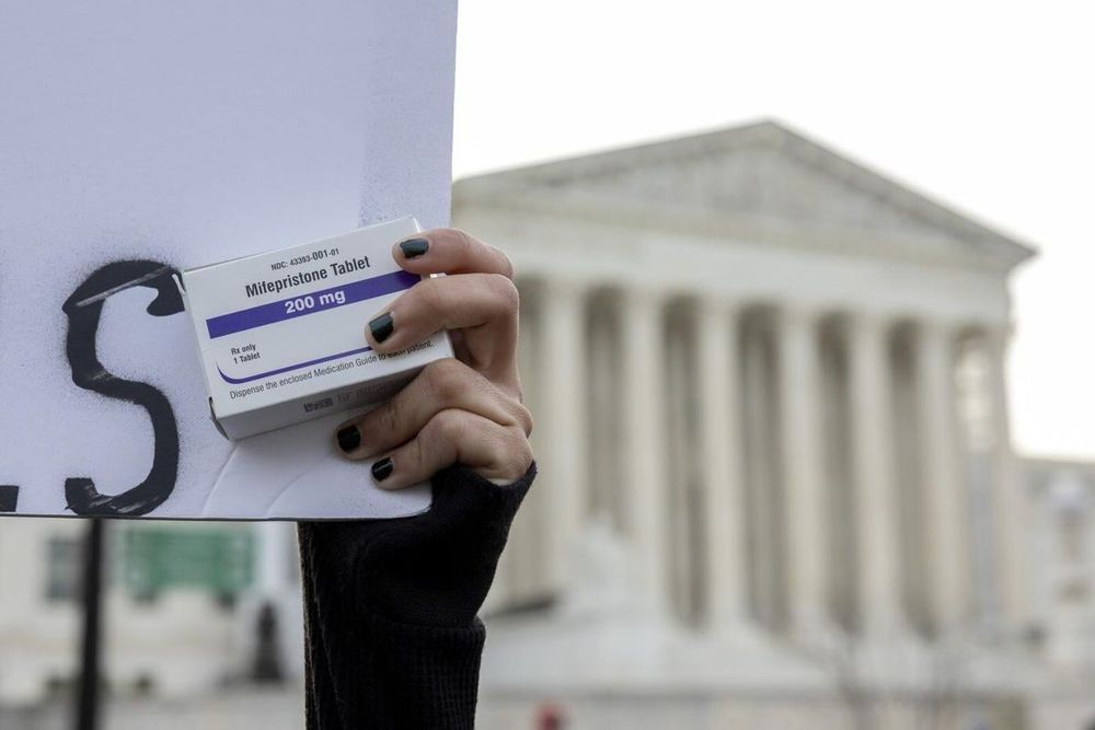 An abortion-rights activist holds a box of mifepristone pills as demonstrators from both anti-abortion and abortion-rights groups rally outside the Supreme Court in Washington, on March 26, 2024. AAR