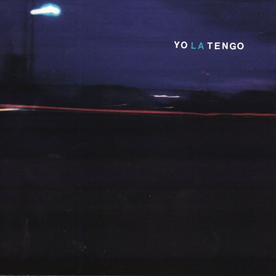 the cover art for yo la tengo's 1993 album "painful"—a long stretch of highway at night, broken up by neon lights from buildings and a passing car.
