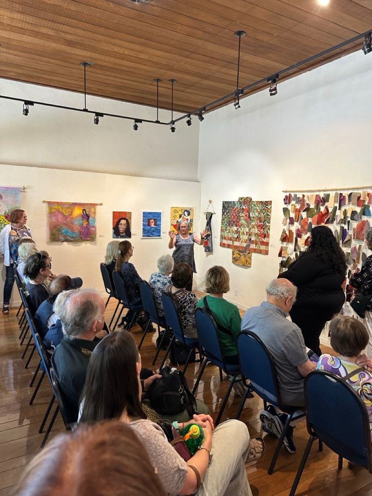 Denise Oyama Miller speaking about her piece "Tattered" in front of a room full of people.