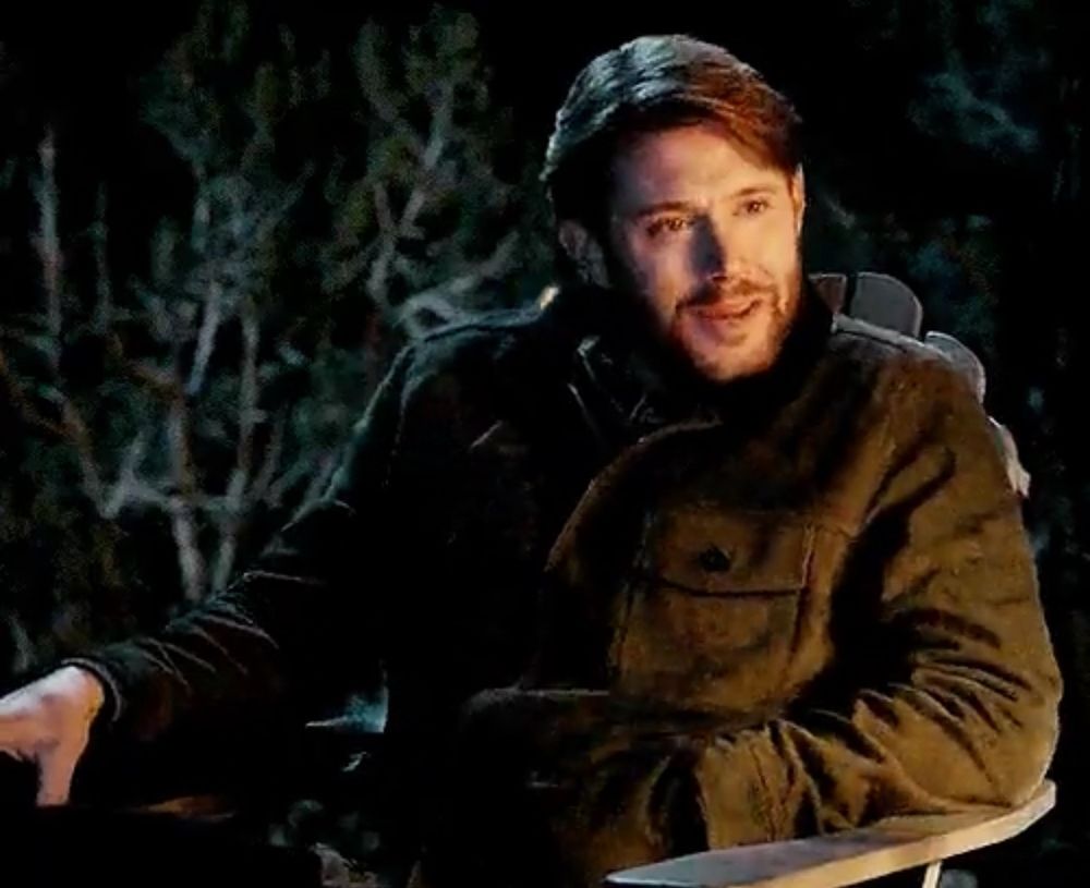 Jensen Ackles sitting in chair in woods 