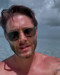 Jensen Ackles shirtless with water in the background 