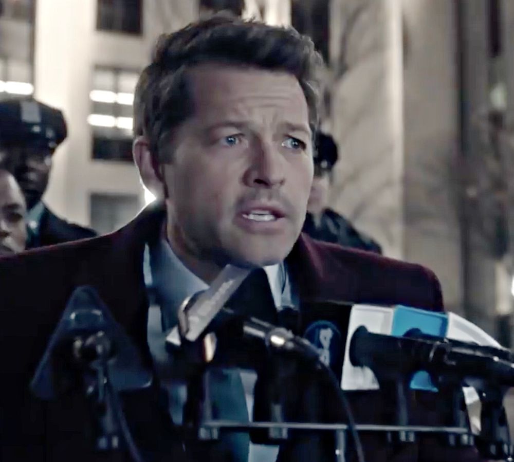 Misha Collins as Harvey dent talking into micron phones 