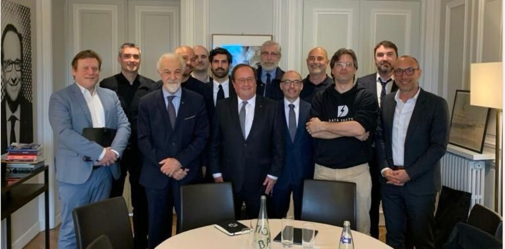 13 hommes blancs cis dont Hollande dans un bureau aux boiseries apparentes.
Petit bonus : un tableau représentant F Hollande au mur 