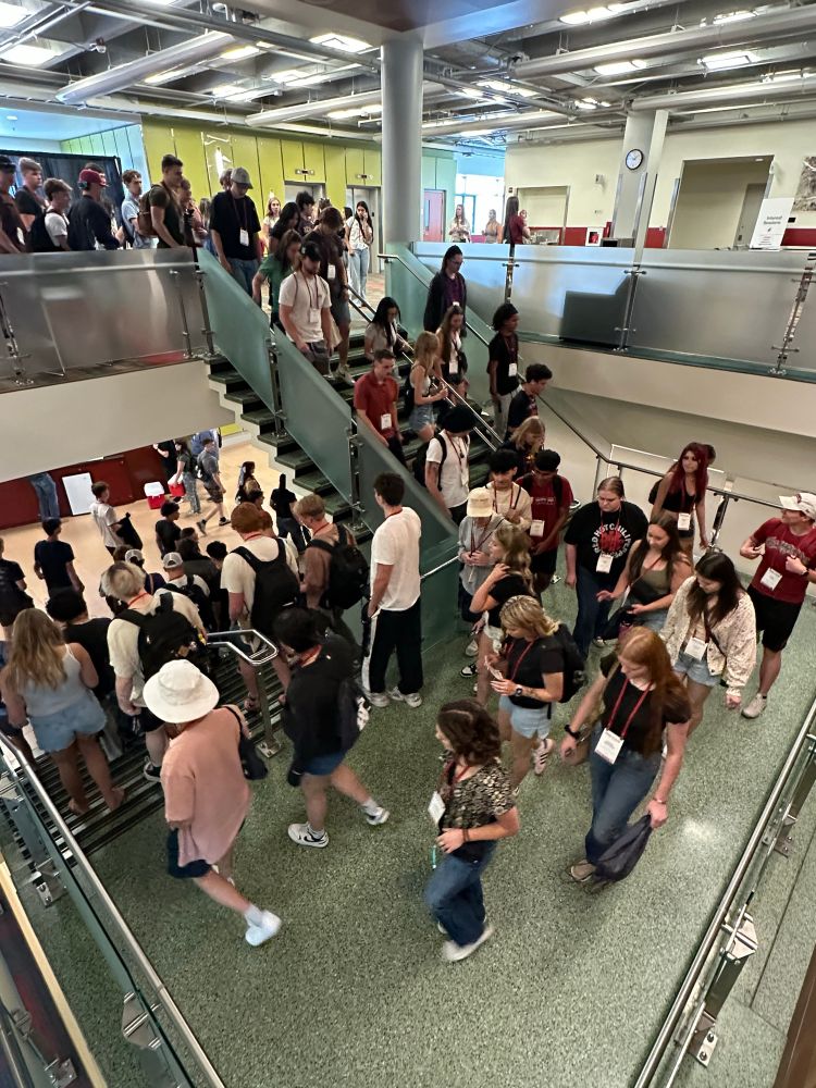 Color indoor photo showing people walking down a green staircase 