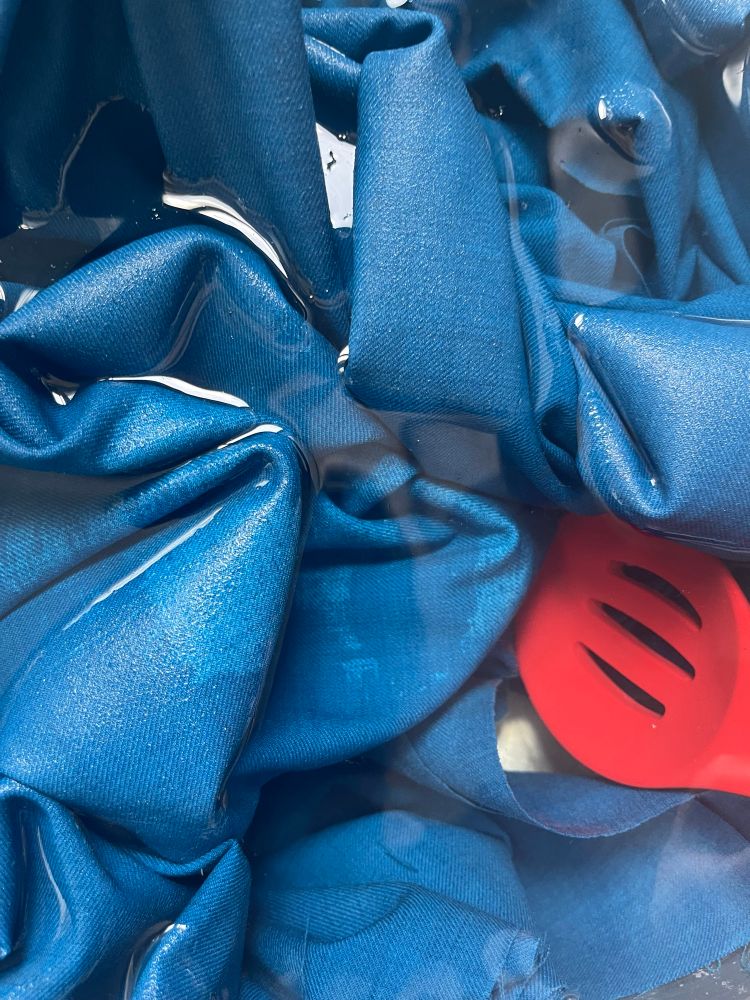 Some cyan fabric submerged in water with some dry spots still cisibke