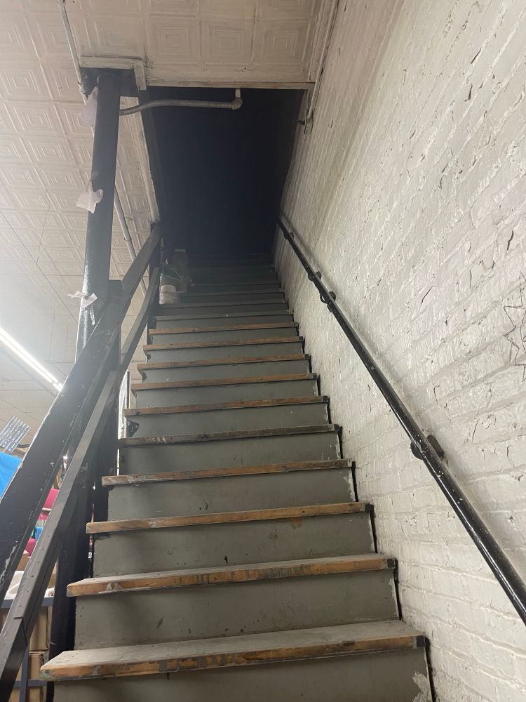 Some old wooden steps with chipping gray paint leading up to a black void