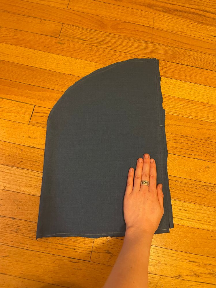 Some very large pockets cut out of blue fabric with my hand on them for scale