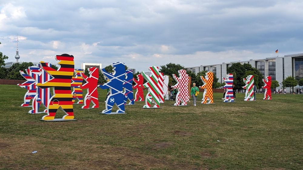 Auf einer Wiese stehen Pappbären in den Farben der Flaggen der europäischen Länder. Im Hintergrund ist der Fernsehturm und das Paul Löbe Haus zu sehen