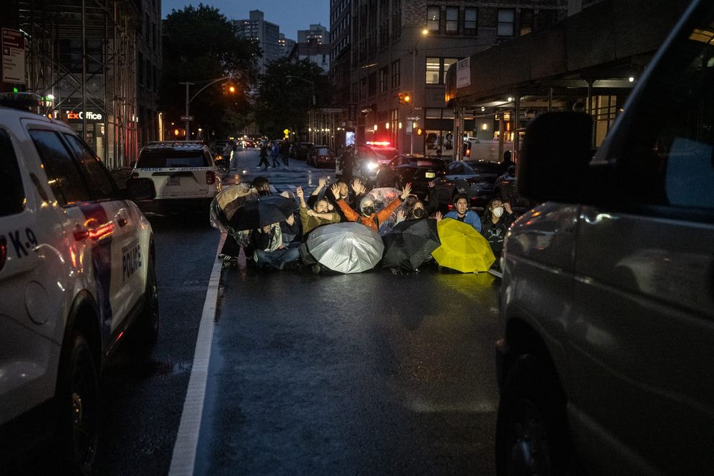 protesters sitting in the middle of the street blocking an ICE van