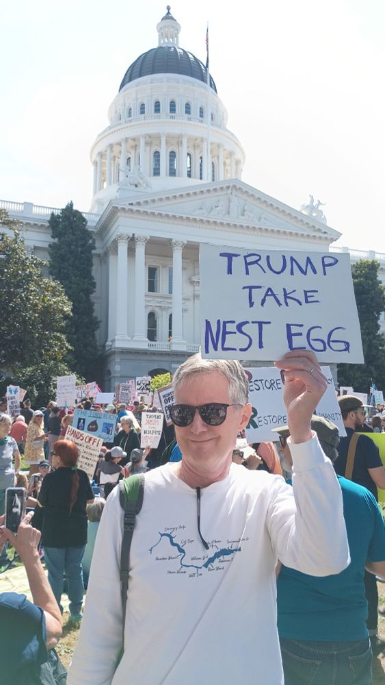Picture of an attendee holding a "Trump Take Nest Egg" sign at the Hands Off rally in Sacramento, CA today.
