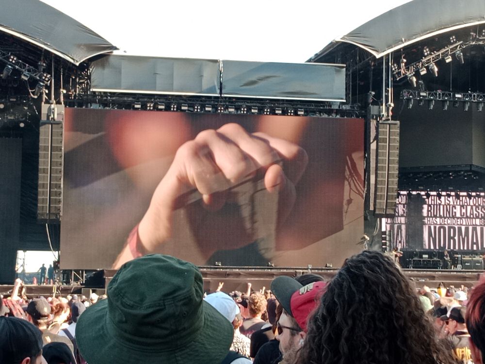 Visual from Refused showing a raised fist. Thousands are shouting "FREE FREE PALESTINE"