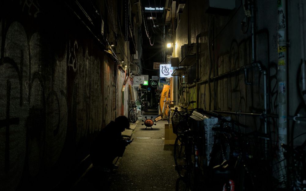 Lucky Day standing in a dimly lit alleyway at night, fearfully clutching his $100 bill.