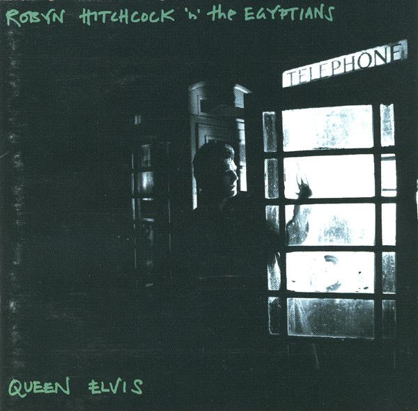 Cover of "Queen Elvis", by Robyn Hitchcock 'n' the Egyptians, showing a photo a man mostly in darkness, looking to his left, with his arm stretching into a telephone booth, the light of which illuminates the left side of his face.