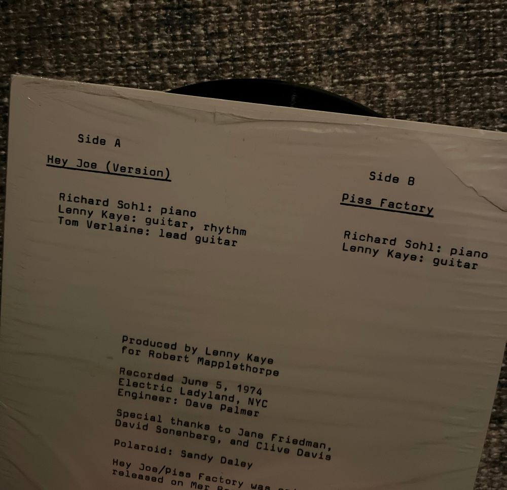 Back cover of a Patti Smith record ‘Hey Joe’ and ‘Piss Factory’, white background with black font.