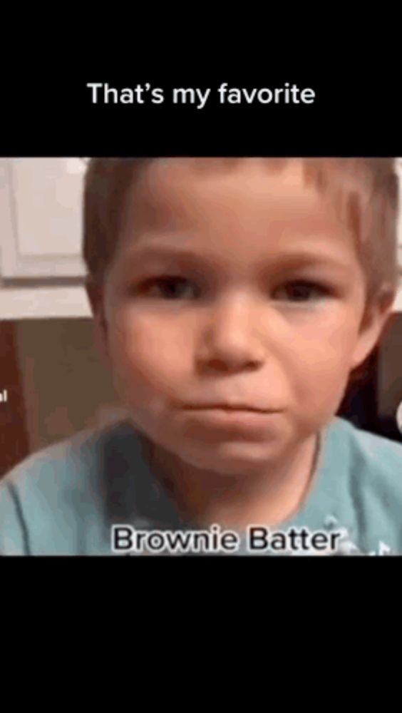 a young boy in a blue shirt is making a funny face and saying `` that 's my favorite brownie batter '' .