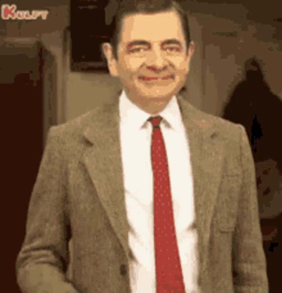 mr bean is wearing a suit and tie and smiling